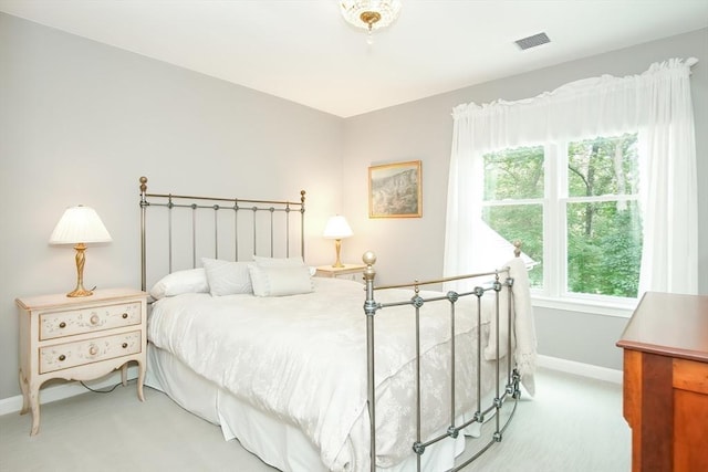 bedroom with baseboards, visible vents, and light colored carpet