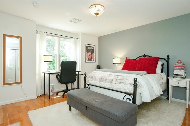 bedroom with visible vents, baseboards, and wood finished floors