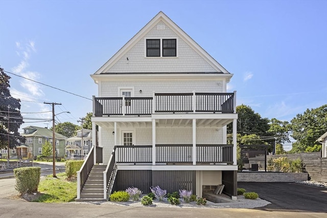 view of front of home featuring aphalt driveway, covered porch, stairs, and a balcony