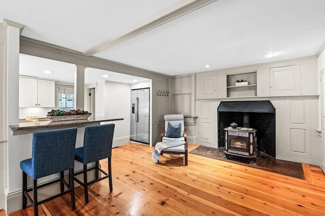 2 Andover St Unit A, Salem, MA 01970 - kitchen with stainless steel fridge, a wood stove, a kitchen breakfast bar, white cabinets, and wood-type flooring