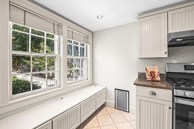 2 Andover St Unit A, Salem, MA 01970 - kitchen with under cabinet range hood, stainless steel gas range, light tile patterned floors, dark countertops, and recessed lighting