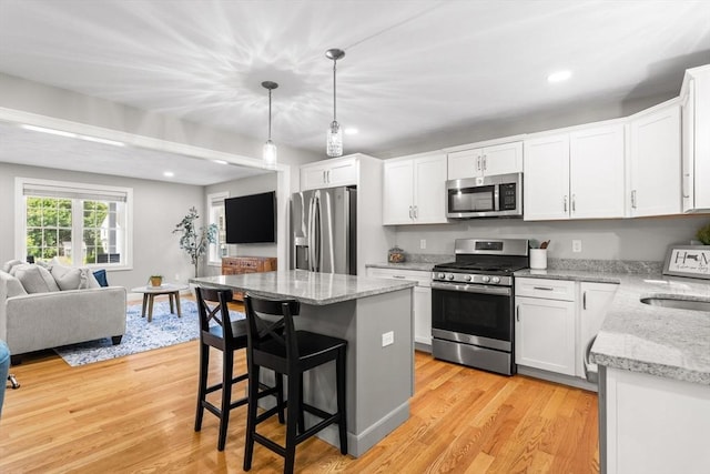 30 Oak Meadow Pl Unit 30, Bridgewater, MA 02324 - kitchen featuring stainless steel appliances, open floor plan, a kitchen island, white cabinetry, and a kitchen breakfast bar
