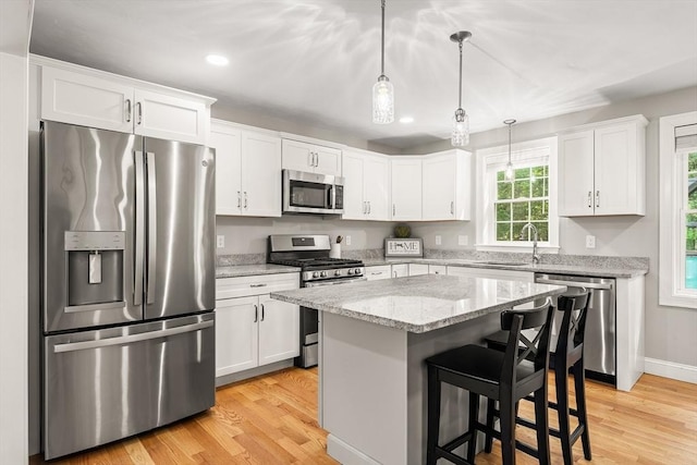 30 Oak Meadow Pl Unit 30, Bridgewater, MA 02324 - kitchen with stainless steel appliances, white cabinets, a breakfast bar, light wood-style flooring, and a center island