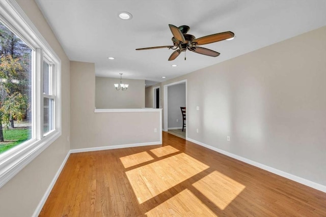 unfurnished room featuring ceiling fan with notable chandelier, baseboards, wood finished floors, and recessed lighting