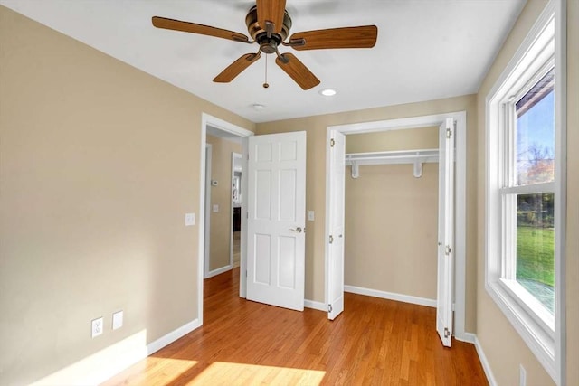 unfurnished bedroom featuring baseboards, a closet, multiple windows, and light wood-type flooring