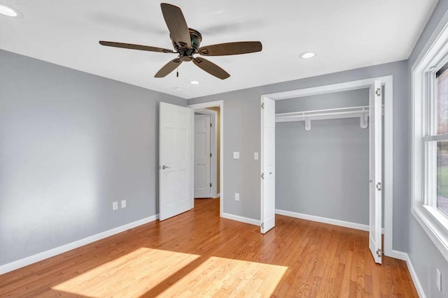 unfurnished bedroom featuring light wood-type flooring, a closet, baseboards, and multiple windows