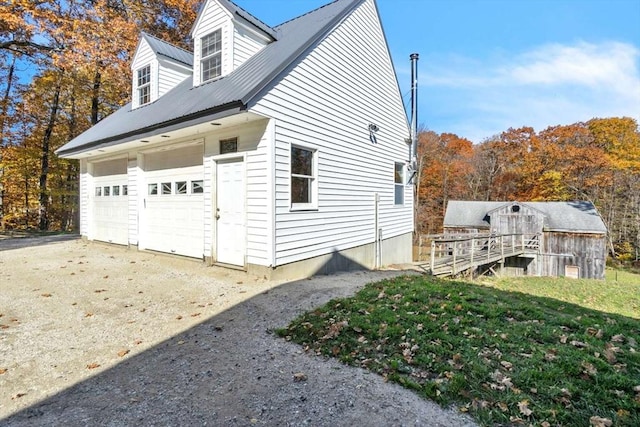view of side of home with driveway and metal roof