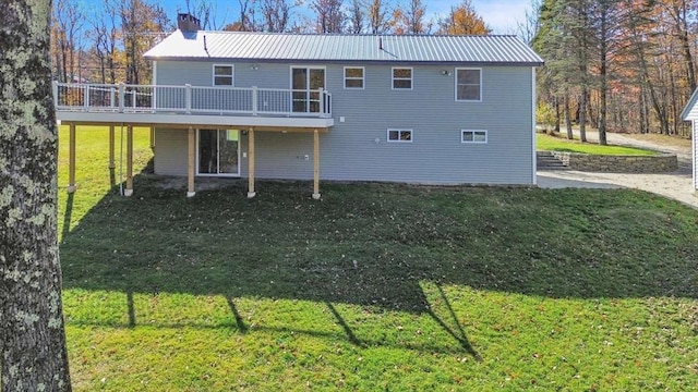 rear view of house with a chimney, a wooden deck, a yard, and metal roof
