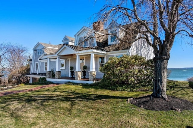 cape cod house with covered porch, a water view, and a front lawn