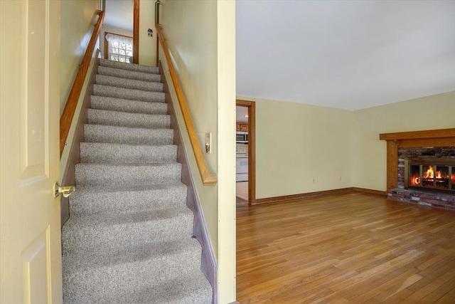 stairs featuring wood finished floors and a fireplace
