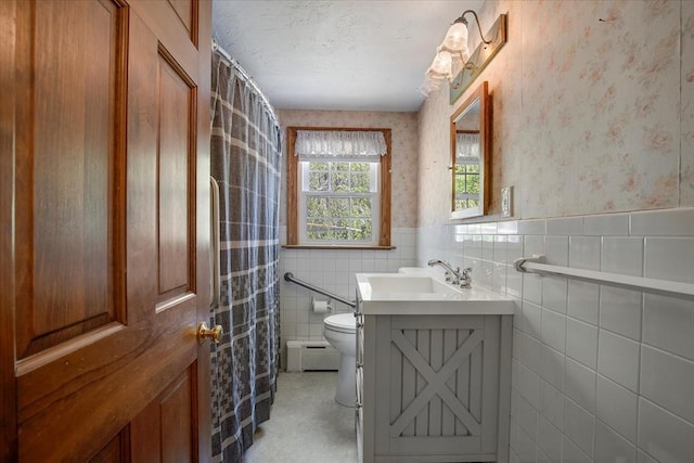 full bath with a baseboard heating unit, toilet, tile walls, vanity, and wallpapered walls