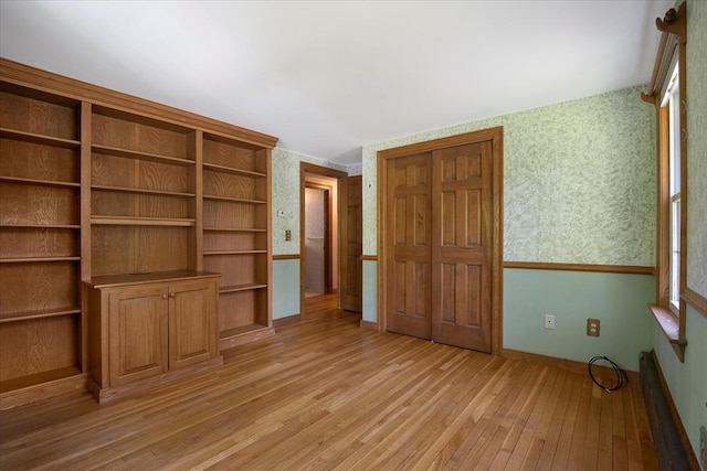 unfurnished bedroom with wallpapered walls, light wood finished floors, and baseboards