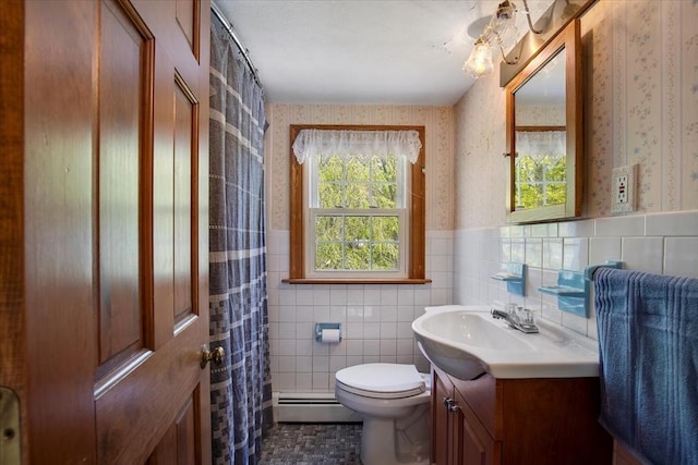 bathroom featuring wallpapered walls, a baseboard heating unit, vanity, toilet, and tile walls