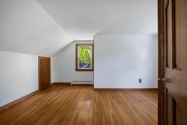 additional living space with a baseboard heating unit, hardwood / wood-style floors, lofted ceiling, and baseboards