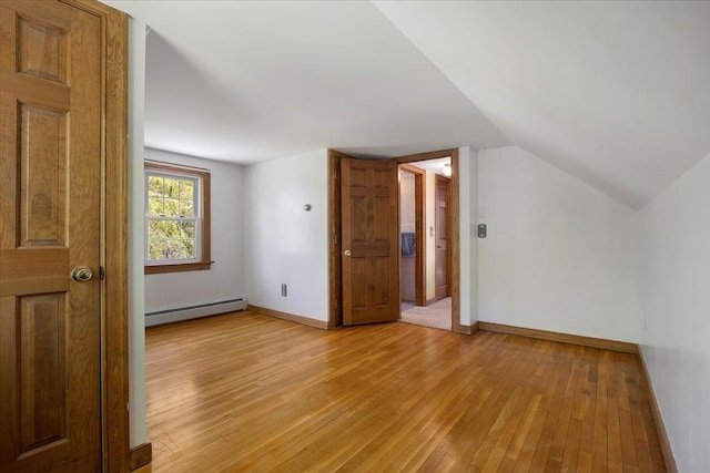 bonus room with a baseboard heating unit, light wood-type flooring, baseboards, and lofted ceiling