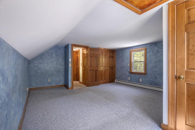 additional living space featuring baseboard heating, lofted ceiling, and carpet floors