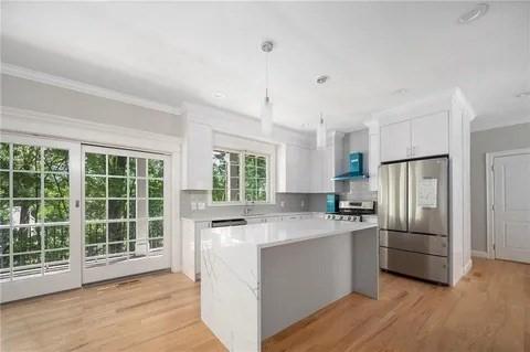 70 Shady Ln, Burrillville, RI 02859 - kitchen featuring freestanding refrigerator, stove, white cabinetry, a center island, and light countertops