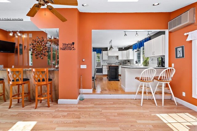 589 Depot St, Harwich, MA 02645 - kitchen featuring light wood finished floors, tasteful backsplash, a peninsula, white cabinets, and ceiling fan