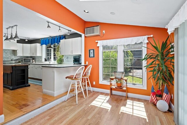 589 Depot St, Harwich, MA 02645 - kitchen with white cabinets, tasteful backsplash, lofted ceiling, and light wood finished floors