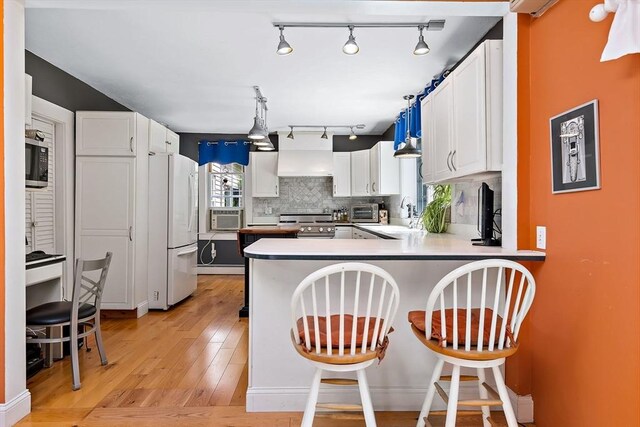 589 Depot St, Harwich, MA 02645 - kitchen featuring white cabinets, a peninsula, tasteful backsplash, appliances with stainless steel finishes, and light wood-style floors