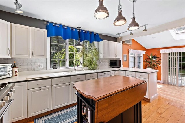 589 Depot St, Harwich, MA 02645 - kitchen featuring white cabinetry, high end stove, lofted ceiling with skylight, and a peninsula