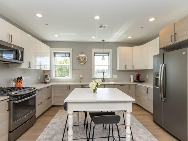 447 Frankfort St Unit 3, Boston, MA 02128 - kitchen featuring appliances with stainless steel finishes, light wood-style floors, decorative backsplash, and recessed lighting