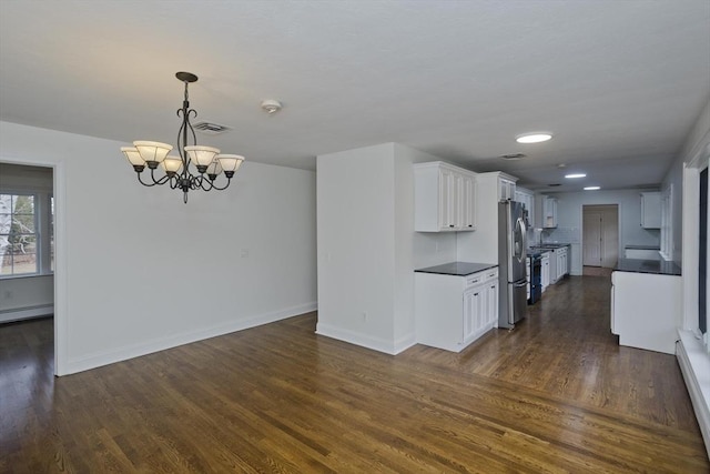 kitchen with dark wood-type flooring, dark countertops, visible vents, and stainless steel fridge with ice dispenser