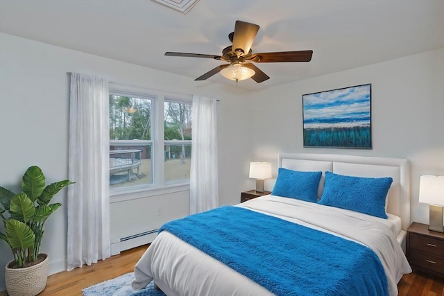 bedroom featuring ceiling fan, baseboard heating, and wood finished floors