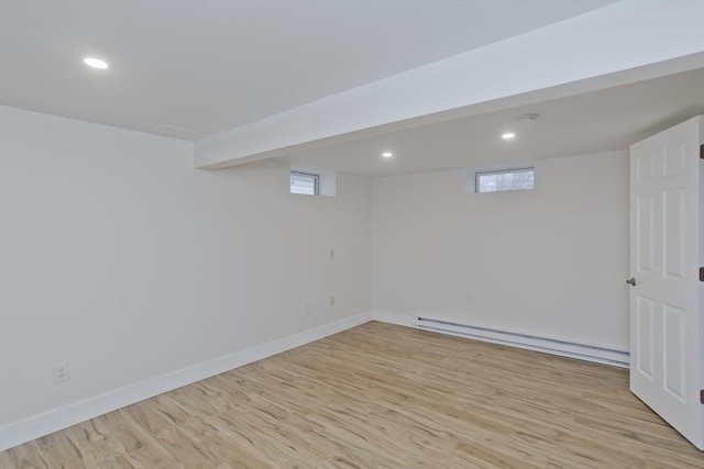 below grade area with recessed lighting, a baseboard radiator, light wood-style flooring, and baseboards