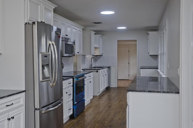 kitchen with stainless steel appliances, a sink, white cabinetry, visible vents, and decorative backsplash