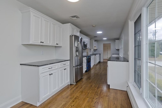 kitchen with visible vents, dark countertops, appliances with stainless steel finishes, dark wood-style flooring, and white cabinetry