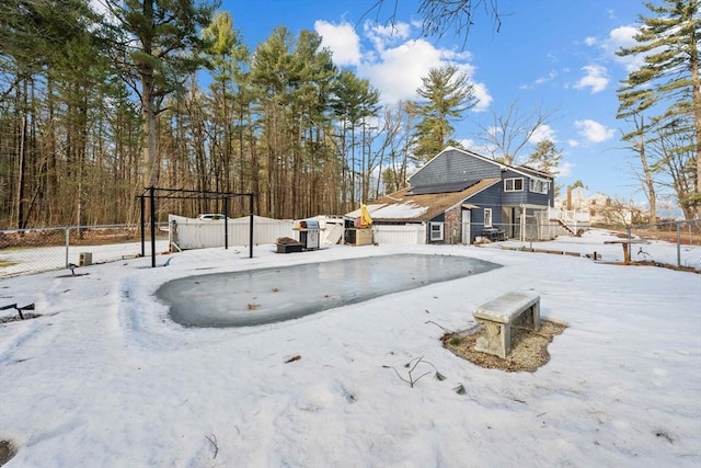 snow covered house with roof mounted solar panels, a garage, and fence