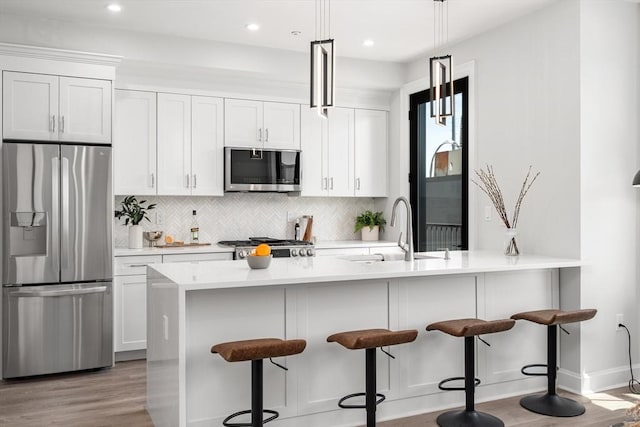 523 2nd St Unit 303, Everett, MA 02149 - kitchen featuring appliances with stainless steel finishes, a sink, light wood-style floors, tasteful backsplash, and light countertops