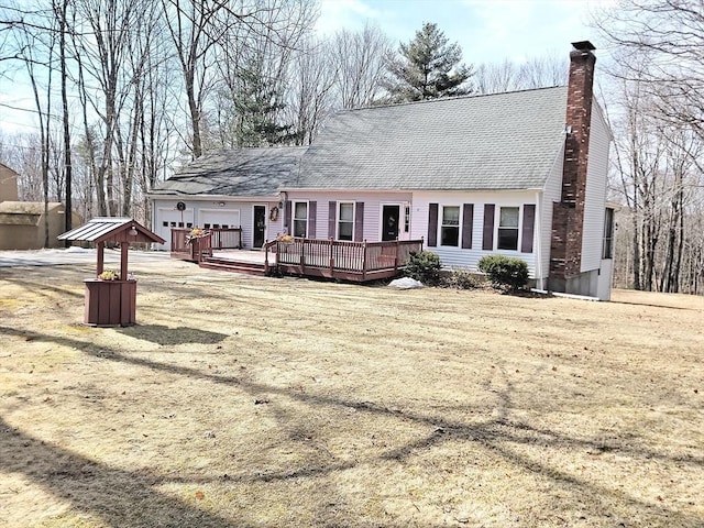 rear view of house featuring a garage, a deck, and a chimney