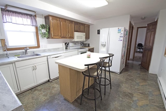 kitchen featuring white appliances, a breakfast bar, a sink, light countertops, and a baseboard heating unit