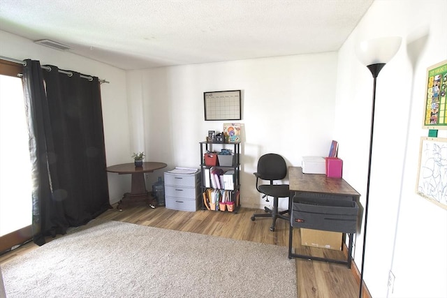 home office with wood finished floors, visible vents, and a textured ceiling