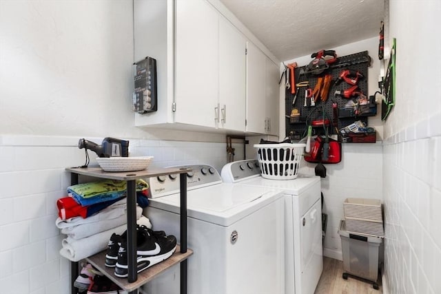 2218 Mystic Valley Pkwy, Medford, MA 02155 - laundry area with washer and clothes dryer, cabinet space, wainscoting, light wood-style floors, and tile walls