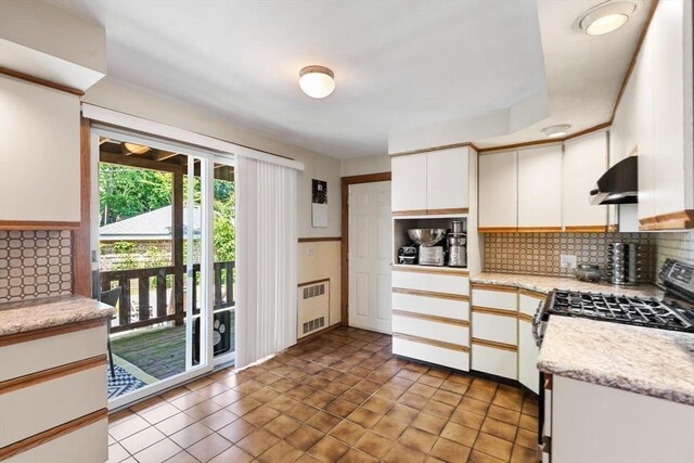 2218 Mystic Valley Pkwy, Medford, MA 02155 - kitchen featuring radiator heating unit, under cabinet range hood, gas range, white cabinets, and backsplash