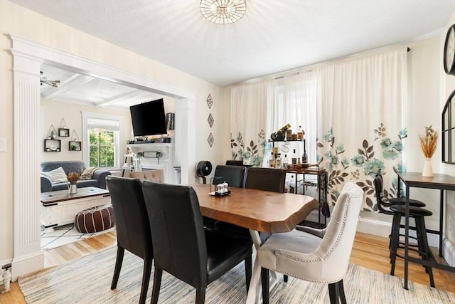 2218 Mystic Valley Pkwy, Medford, MA 02155 - dining space with wood finished floors, a fireplace, baseboards, beam ceiling, and decorative columns