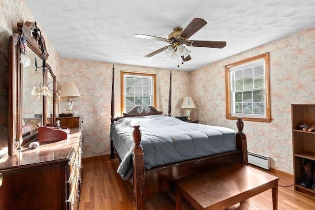 196 Plymouth Ave, Quincy, MA 02169 - bedroom featuring wood finished floors, a baseboard radiator, wallpapered walls, baseboards, and a textured ceiling