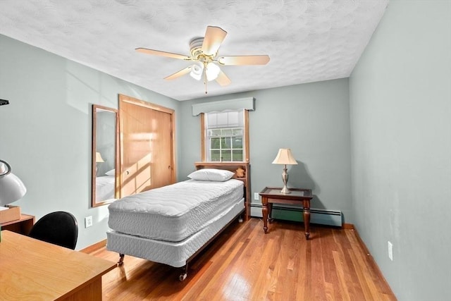 196 Plymouth Ave, Quincy, MA 02169 - bedroom featuring a baseboard heating unit, wood finished floors, a textured ceiling, an office area, and a closet