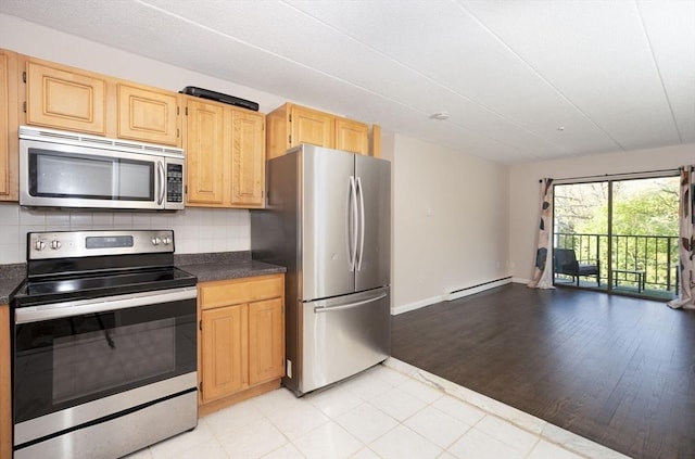 kitchen with dark countertops, stainless steel appliances, baseboard heating, and backsplash