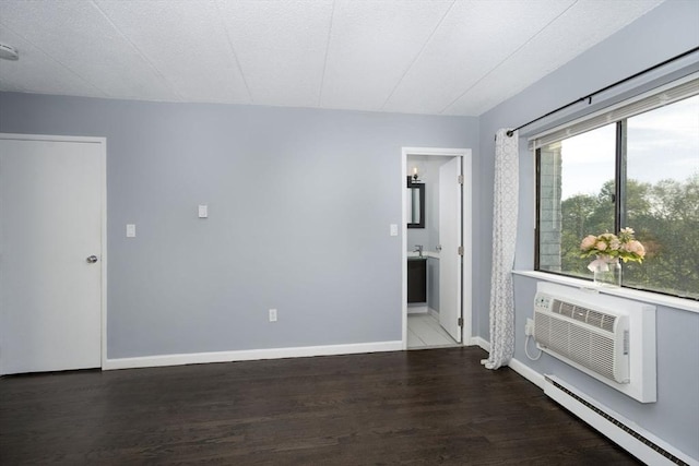 unfurnished room featuring a baseboard radiator, a wall mounted AC, baseboards, and wood finished floors