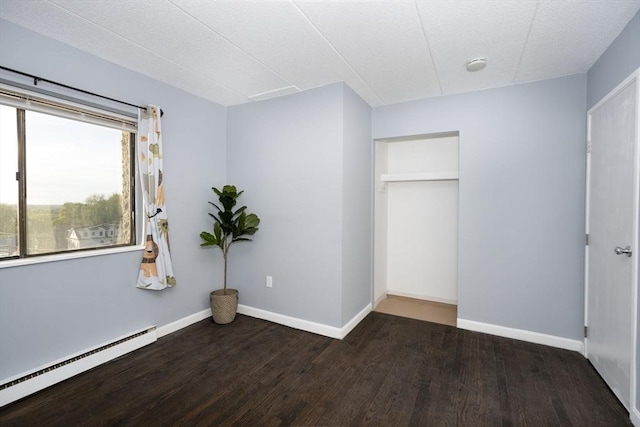 unfurnished bedroom with baseboards, wood finished floors, and a baseboard radiator