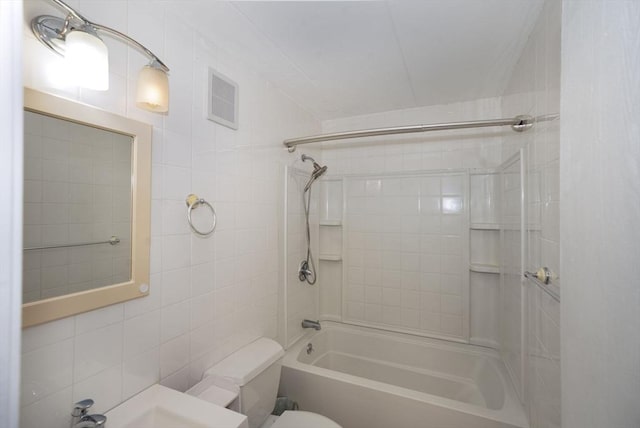 bathroom featuring tile walls, toilet, visible vents, and bathing tub / shower combination