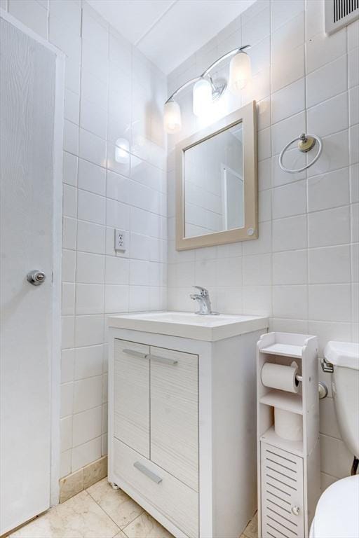 bathroom featuring vanity, tile walls, toilet, and visible vents