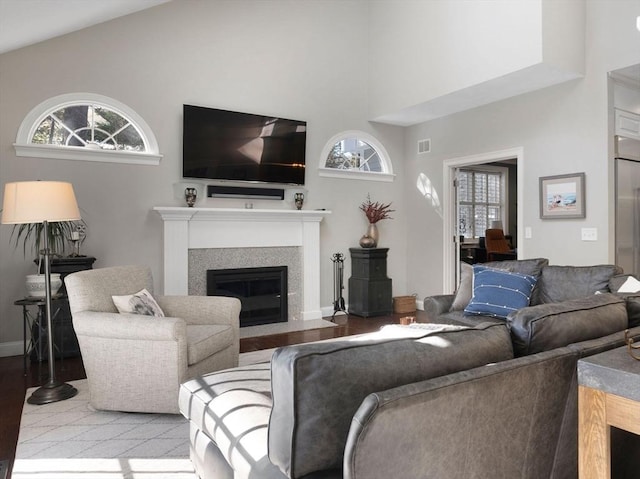 living area featuring a glass covered fireplace, baseboards, visible vents, and light wood finished floors