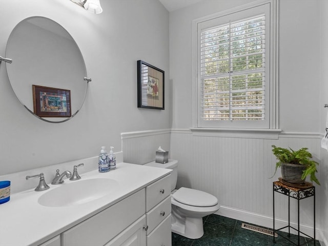 half bath with plenty of natural light, wainscoting, and toilet