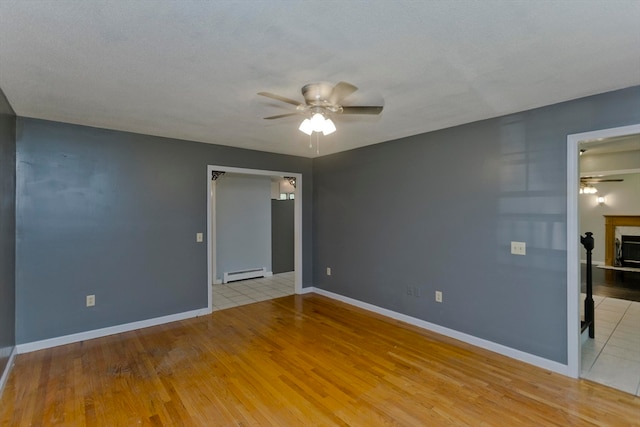 spare room with ceiling fan, a textured ceiling, light wood-type flooring, and a baseboard heating unit