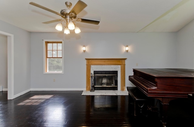 living room featuring dark hardwood / wood-style floors, ceiling fan, and a premium fireplace